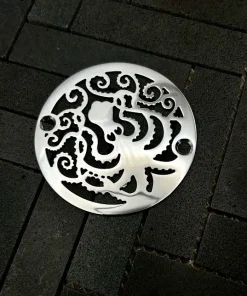 Round drain with octopus design in polished stainless steel finish.