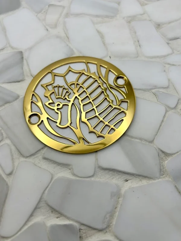 Round drain with seahorse design in polished brass finish.
