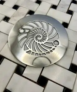 Round drain with nautilus design in polished stainless steel finish.