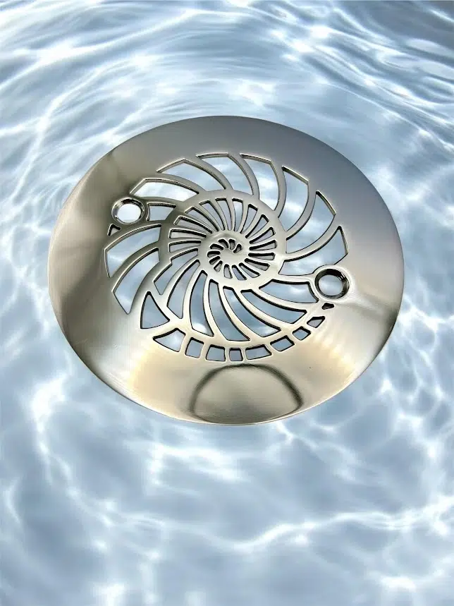 Round drain with nautilus design in polished stainless steel finish.