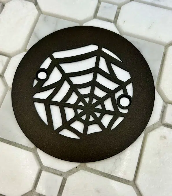 4.25 round spider web oil rubbed bronze on white tile