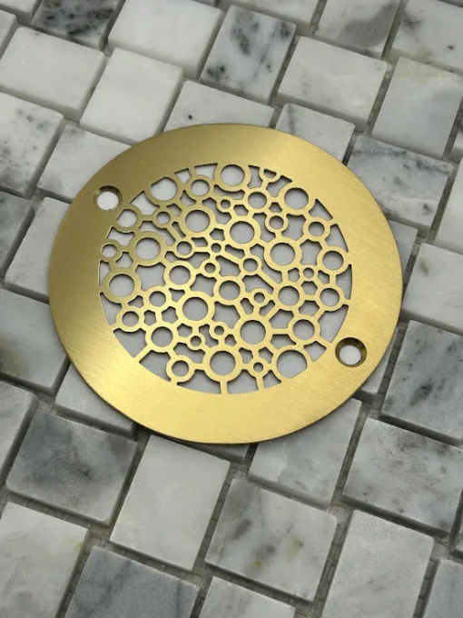 Round drain in a brushed brass finish.