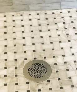 Geometric No. 1 4.25 round shower drain in brushed stainless steel installed on black and white tile