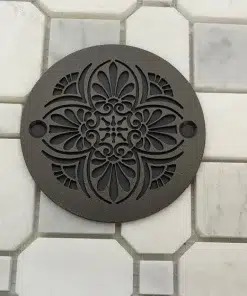 Greek Anthemion 3.25 inch round shower drain in oil-rubbed-bronze on white tile and black background.