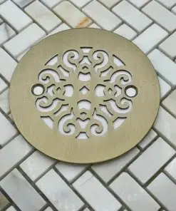 Scrolls No. 4, 4.25-inch round shower drain in champagne bronze on tile.
