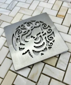 Square drain with octopus design in brushed stainless steel finish.