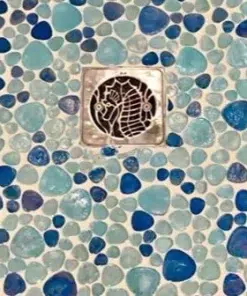 Seahorse square shower drain cover in polished stainless steel, installed on a ocean blue tile.