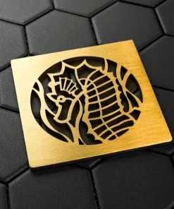 Seahorse square shower drain cover in brushed brass on black tile