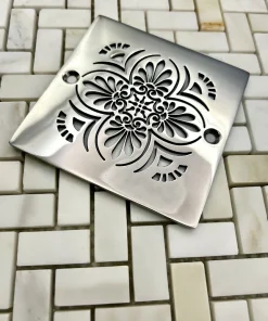 Square drain with greek anthemion design in polished stainless steel finish.