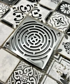 Square drain with maze design in polished stainless steel finish.