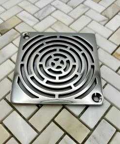 Square drain with maze design in polished stainless steel finish.