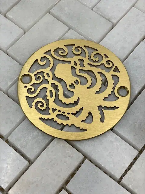 Octopus 3.25 round shower drain brushed brass on white tile