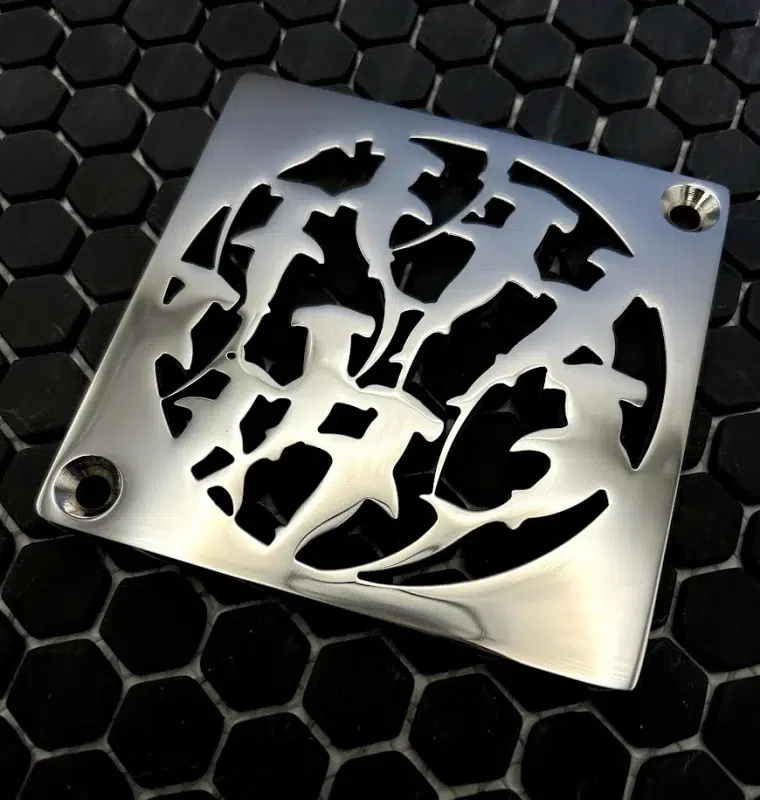 Square drain with sharks design in polished stainless steel finish.