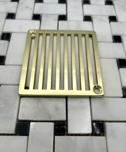 square drain with vertical lines in unlacquered brass finish.