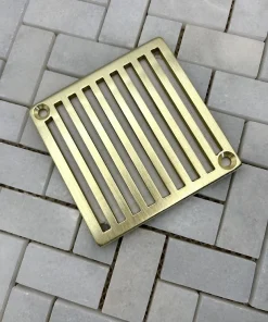 square drain with vertical lines in unlacquered brass finish.