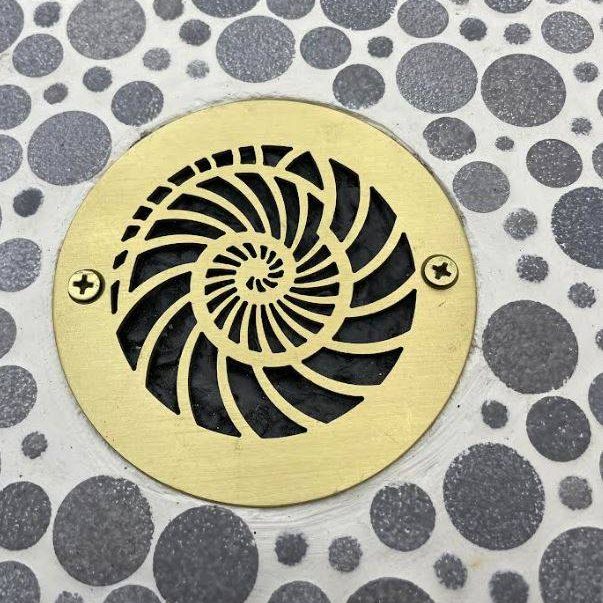Nautilus Design 4 inch Round Brushed Brass on tile Designer Drains.