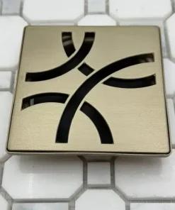 Kerdi-Drain Tile Shower Grate Kit 4″. Finish in Champagne Bronze by Designer Drains on white tile.