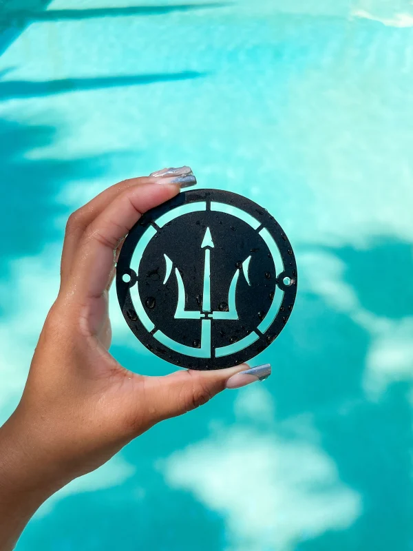 matte black NDS outdoor drain with cut out trident design, with swimming pool in the background