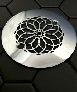 Round drain with mandala design in polished stainless steel finish.
