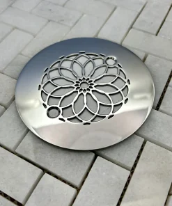 Round drain with mandala design in polished stainless steel finish.