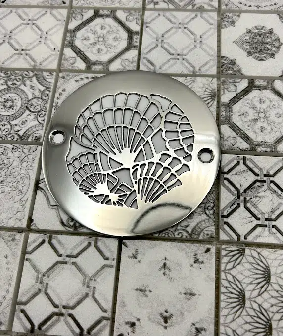 Round drain in polished stainless steel finish.