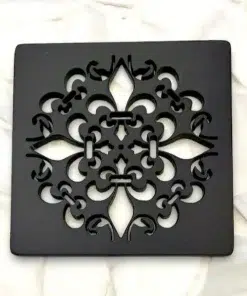 Fleur De Lis square shower drain cover in a matte black finish on white tile.