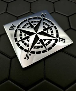 Square drain with compass rose design in polished stainless steel.