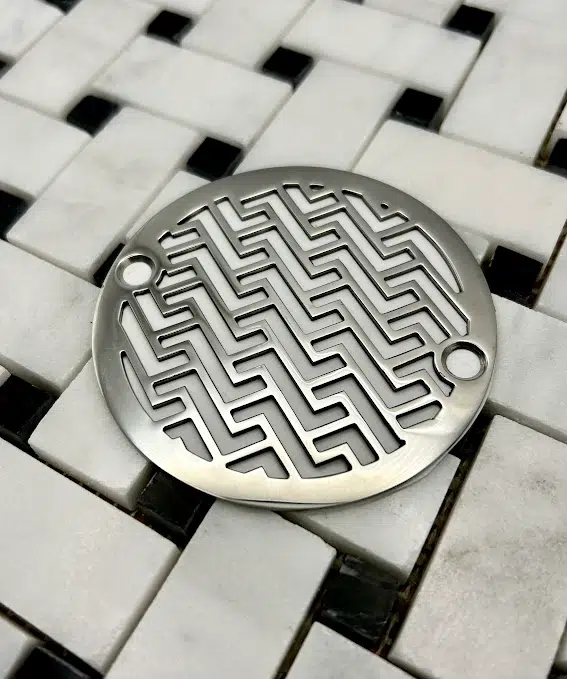 Round drain in polished stainless steel finish.