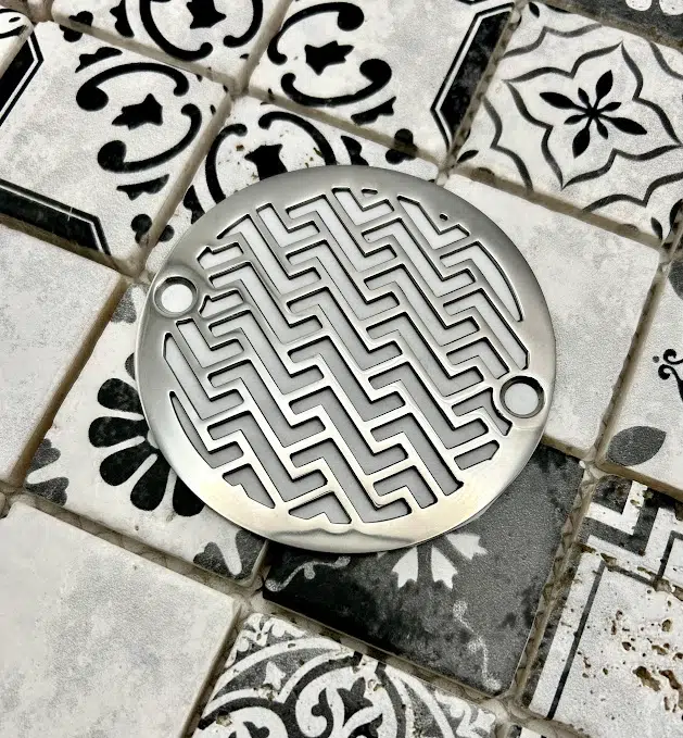 Round drain in polished stainless steel finish.