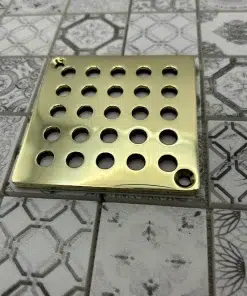 Square drain with geometric circle design in unlacquered polished brass finish.