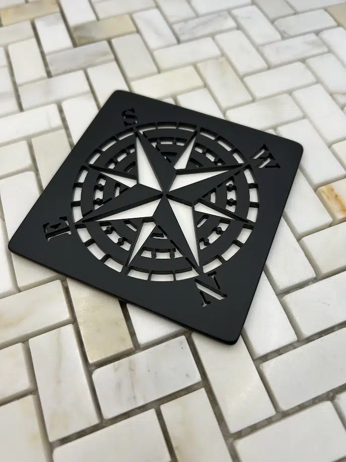 compass rose design in matte black finish on off white tile