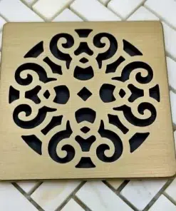 Scrolls No. 4 square shower drain in champagne bronze finish set on tile with black background