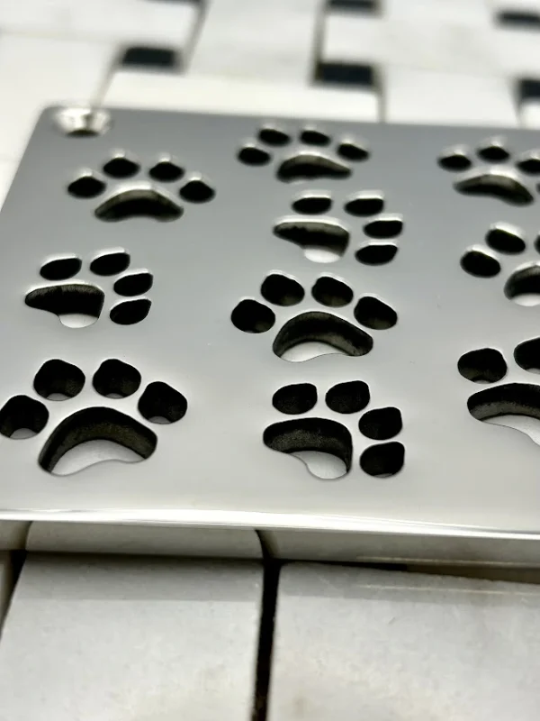 Square drain with dog paws design in polished stainless steel finish.