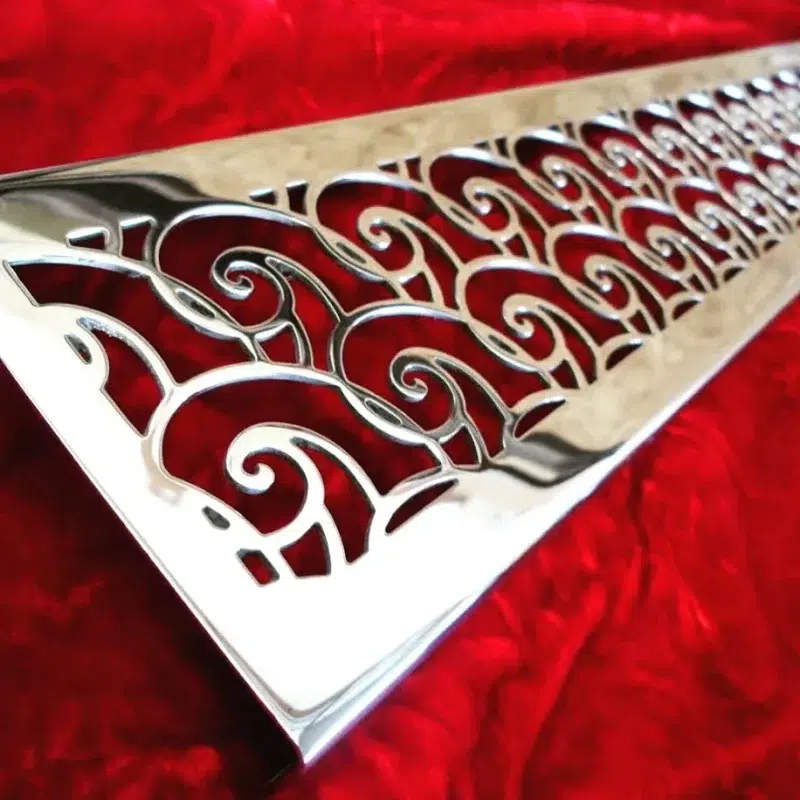 Linear drain wth waves design in polished stainless steel finish.