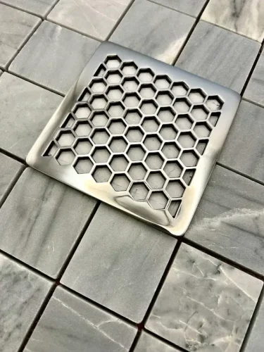 Square drain in honeycomb design with polished stainless steel finish.